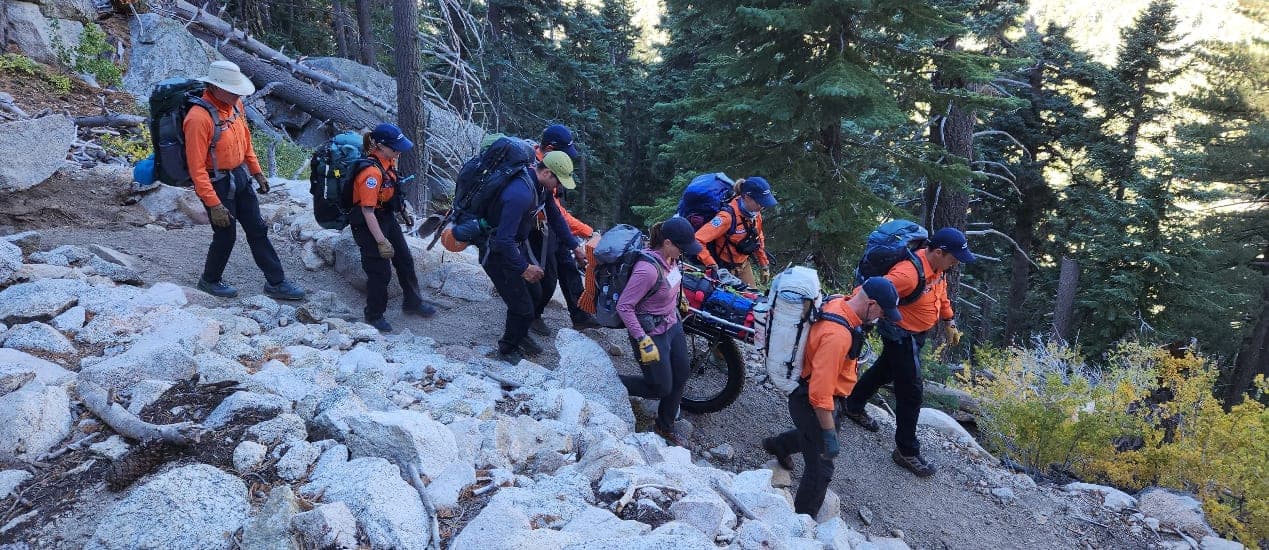Team members carrying a litter over rough terrain